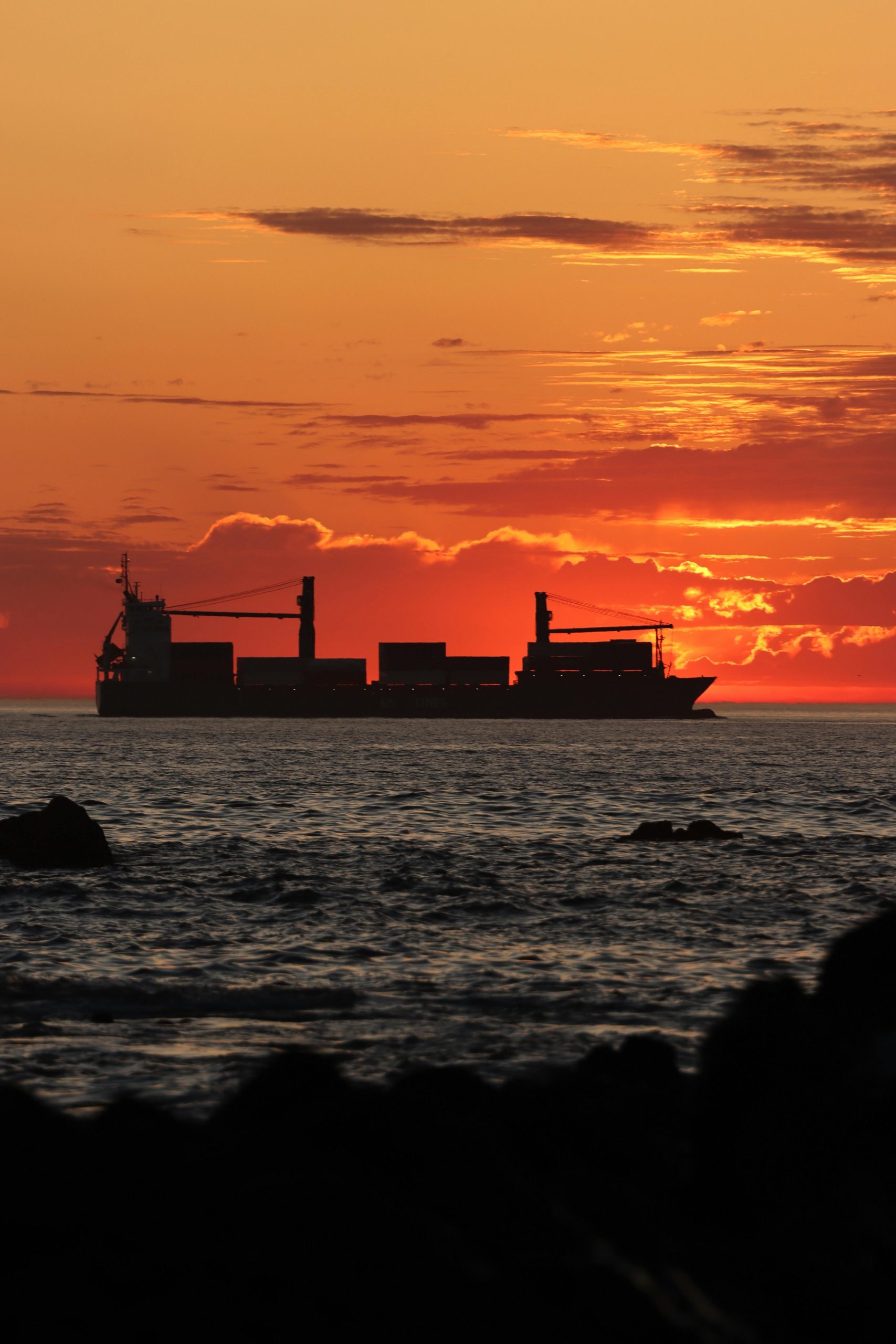Cargo ship on sea with sunrise in the background